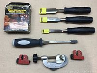 Overview of all tools including rotary pipe cutter, three smaller red pipe cutters, and four chisels with three having yellow blade covers.
