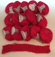 15 balls of raspberry-colored Nashua Handknits Creative Focus Kid Mohair yarn laid out with one knitted swatch sample.