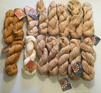 Full spread of all 15 skeins showing oatmeal, gold and ivory colors with labels