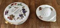 Photo showing covered casserole dish and juicer side by side on wood surface for size and pattern view.