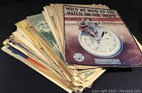 A large stack of vintage sheet music with an example titled 'When We Wind Up the Watch on the Rhine' on top