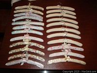 Full view of 23 fabric covered padded hangers arranged in rows on a dark wooden surface showing floral prints and satin covers in pastel colors.