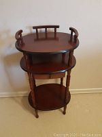 Full view of the small wooden accent table with three tiers and a drawer in the middle tier.