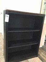 Front view of black bookcase showing three shelves.