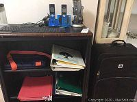 Photo of office shelving including roll-up keyboard, cordless phones, desktop keyboard, binders, and folders