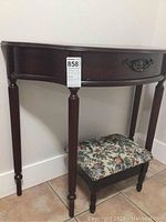 Half entryway side table with dark wood finish, curved front, fluted legs, and one drawer with decorative pull.