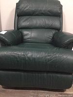 Front view of dark green leather recliner showing padded headrest, arms, seat