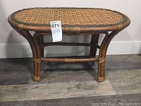 Side view of wicker table showing overall shape and construction with curved legs and cross supports.
