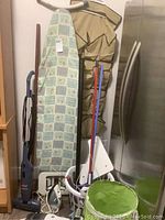 Photo of ironing board, vacuum cleaner, laundry baskets, curtain rods and cleaning accessories grouped together