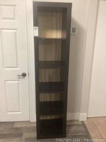 Front view of tall black shelving unit with four open shelves and light wood-toned back panel.