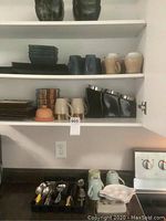 Full view of upper kitchen cabinet with ceramic mugs, bowls, and canisters, plus kitchen counter with cutlery organizer and additional mugs and plates.