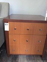Front view of the wooden side table showing two drawers, each with three metal knobs.