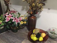 Artificial flower arrangements in vases including pink lilies, yellow flowers, brown ribbed vase, and other smaller vases