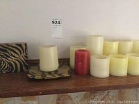 Shelf display showing 8 flameless candles in cream and red colors, along with a decorative tray and a patterned box beside them