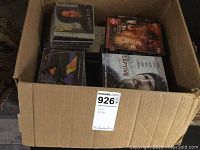 Box containing CDs and DVDs, various artists and movies, with visible cover titles.