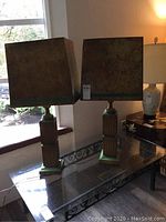 Pair of vintage wooden lamps on glass table near window, showing full lamp and shade detail.