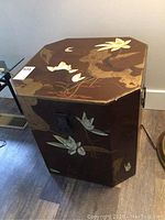 Side and top views of octagonal Asian trunk with lotus flower painted design in gold and white on brown background. Lid detached but shown nearby.