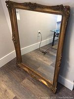 Front angled view of framed mirror leaning against wall, showing overall size and frame details.