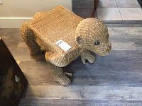 Side view of the monkey-shaped wicker stool showing the woven wicker legs and body structure.