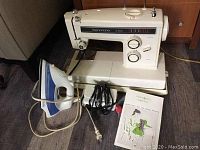 Kenmore sewing machine with iron and manual shown with machine on a table