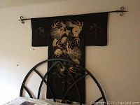 Full view of the black silk kimono hung on the wall showing embroidered dragon design