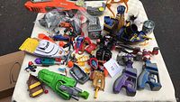 Wide view of assorted children's toys including toy boats, guns, action figures, accessories on a table