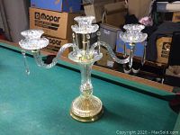 Crystal candelabra displayed on a green pool table, showing full front and side views including base, arms, and decorative hanging crystal pendants.