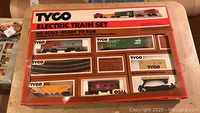 Boxed Tyco Electric Train Set in HO Scale, sealed, with multiple train cars visible through plastic window and orange/red box design.