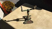 Top angle of the Rain King metal sprinkler showing two nozzle arms and rusty metal base on a beige surface.