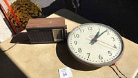 Photo showing both the Simplex wall clock and the vintage tabletop radio side by side on a table outdoors.