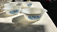 Close-up of four white milk glass Fire King bowls with classic blue cornflower pattern on each side