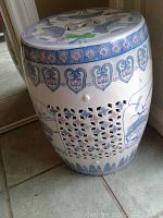 Porcelain garden stool showing side view with painted floral and bird motifs and lattice cut-outs.