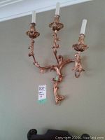 Pair of Italian gilded carved wood wall sconces with three candle arms each, mounted on a wall.