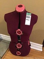 Front view of adjustable dressmaker mannequin with burgundy fabric and pink adjustment knobs at the neck, bust, waist, and hips.