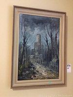 Framed acrylic painting of a landscape with trees and building, mostly blue-gray tones, hung on a wall.