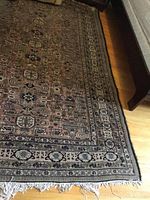 Lower section showing cream border, fringed edge and part of geometric pattern on hardwood floor