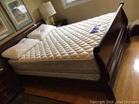 Angle view of assembled sleigh bed frame with mattress and pillows