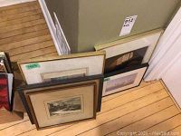 Multiple framed black and white prints leaning against a wall, showing overall lot contents and condition.