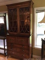 Full front view of entire desk and hutch, showing wood finish, drawer arrangement, and glass door design.