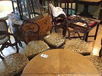 Five antique rosewood chairs with tufted gold-brocade upholstery seats arranged in a room with hardwood flooring, showing walnut finish frames and casters.