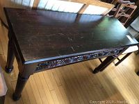 Front angle view of the antique wooden console table showing the ornate carved apron and turned legs.