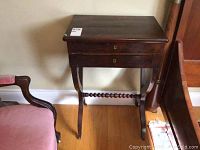 Front and side angled view of antique mahogany table showing crossed legs, drawer with keyholes and polished top.