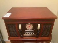 Front view of the wooden music center showing the brown finish, speakers, and analog AM/FM dial.