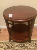 Front view of the round wooden side table showing the tabletop and legs.