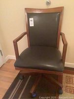 Full view of wood framed desk chair showing leather-like upholstery and caster wheels.