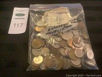 Plastic bag filled with European coins and some silver dollars along with stamps inside the bag.
