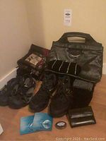 Photo showing black Keen sandals, New Balance shoes, purses including Derek Alexander wallet, evening bag, lunch bag, scarves, gloves, and small accessories arranged on floor.