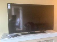 Full front view of TV on table with remote and manual visible