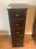Front view showing the five drawers with brass-colored knobs and dark wood finish