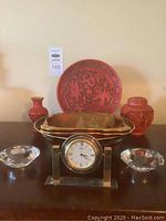 Front view of the lot showing carved plate, vase, jar, Carlton Ware bowl, Seiko clock and glass candle holders on a table.